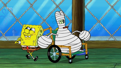 Bob Esponja y un personaje vendado en silla de ruedas, con partes del cuerpo visibles a través del vendaje, interactúan en un espacio interior.