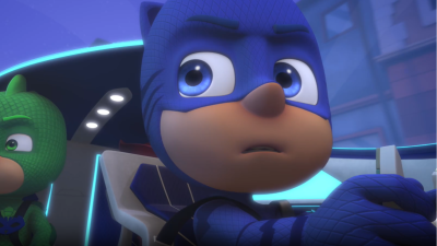 Catboy y Gekko de PJ Masks en la cabina de un vehículo futurista. Catboy, con máscara azul, se concentra en los controles, mientras Gekko, con máscara verde, observa atento.